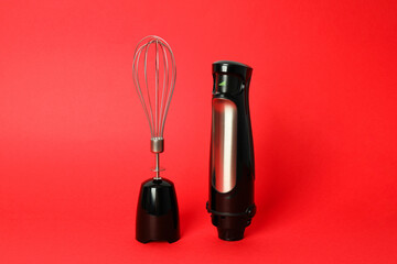 Black blender with whisk on red background