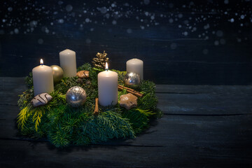 Green advent wreath with white candles, two are lit for second advent, Christmas decoration and cookies, dark blue wooden background with star bokeh, copy space - obrazy, fototapety, plakaty