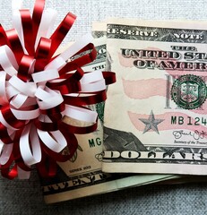 Red white ribbon ball with cash dollars money on gray background  - concept of bonus , money gift,...