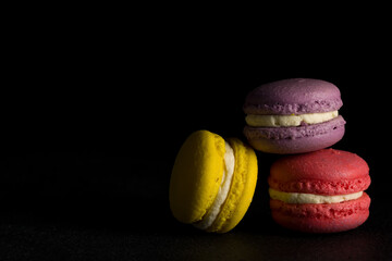 Colored macaroons. Colorful macaroons stacked in a pile on black background