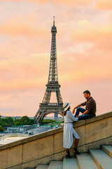 Fototapeta na wymiar Young couple by Eiffel Tower at Sunrise, Paris Eifel Tower Sunrise man woman in love, valentine concept in Paris the city of love. Men and women visiting the Eiffel Tower at sunrise
