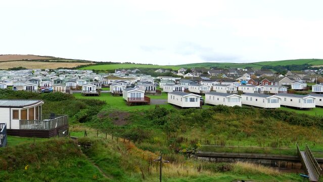 Elevated view of seaside resort St. Bees village caravan park at high tide, Irish Sea coast, Cumbria, North West of England, panning shot.