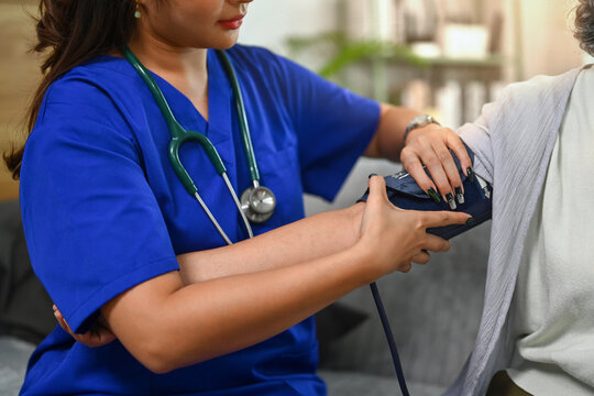 Female nurse measuring blood pressure to senior woman during home visit. Health care service concept