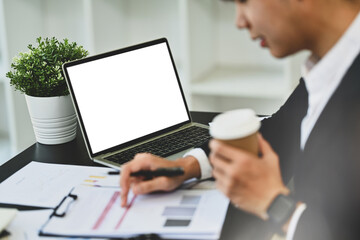 Obraz premium Side view of businessman reading financial reports and working with laptop at desk