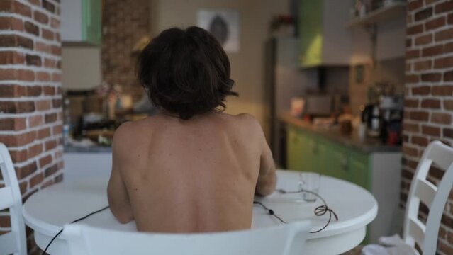 man with a curved spine with scoliosis sits at a table