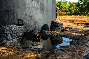 Fresh oil leaking from tank in oil field, environment concept