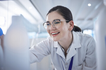 Woman, medical scientist and in lab happy for vial discovery or research future vaccine, review or technology. Female person, glasses and study breakthrough for antibiotic, help job or innovation - obrazy, fototapety, plakaty