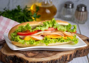 Cheese, ham, lettuce and tomato slices in an appetizing tasty sandwich.