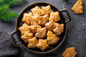  Festive Christmas cookies decorated with golden icing in a black plate. Dark grey background, top view