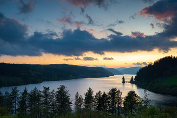 Obraz premium Lake Vyrnwy, located in mid Wales, an area of outstanding natural beauty, at sunset. The orange sky is reflected in the calm water of the lake