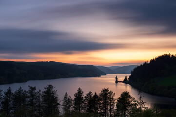 Lake Vyrnwy, located in mid Wales, an area of outstanding natural beauty, at sunset.  The orange sky is reflected in the calm water of the lake