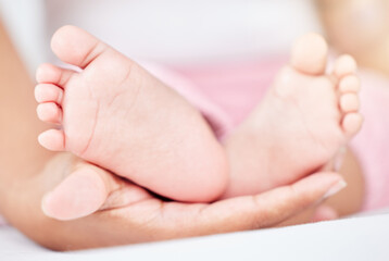 Fototapeta na wymiar Family, care and the feet of a baby in the hands of a parent closeup in the bedroom of their home together. Kids, love or wellness and an infant child on a bed in an apartment with an adult person