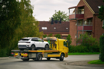 A car with a broken engine on the road, being towed by a truck to a repair shop, as part of the...