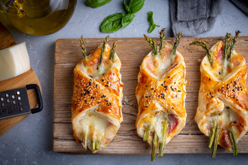 Baked green asparagus with ham and cheese in puff pastry sprinkled with sesame seeds and green...