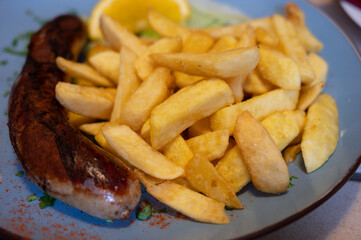 Fried fries potatoes with grilled meat German sausage served in old restaurant in Germany