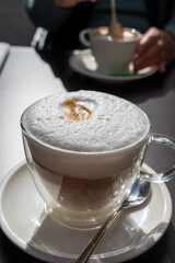 Drinking tasty fresh brewed Italian caffe latte coffee with whipped milk in outdoor cafe