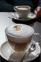 Drinking tasty fresh brewed Italian caffe latte coffee with whipped milk in outdoor cafe