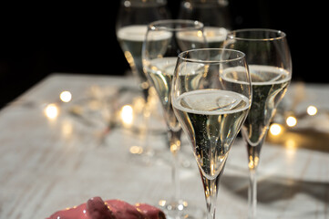 New year party, small bubbles of brut champagne cava or prosecco wine in tulip glasses with garland...