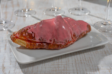 New year party, sweet dessert pink creamy croissant and brut champagne cava or prosecco wine in tulip glasses with garland  lights