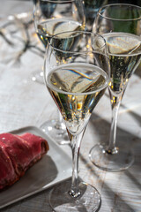 New year party, small bubbles of brut champagne cava or prosecco wine in tulip glasses with garland  lights on background