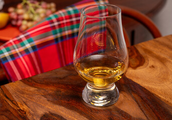 Tasting of different Scotch whiskies strong alcoholic drinks, drum of whiskey and colorful Scotch tartan on background close up