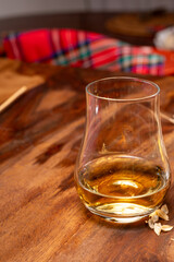 Tasting of different Scotch whiskies strong alcoholic drinks, drum of whiskey and colorful Scotch tartan on background close up