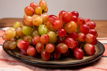 Sweet washed ripe pink grapes berries on board ready to eat