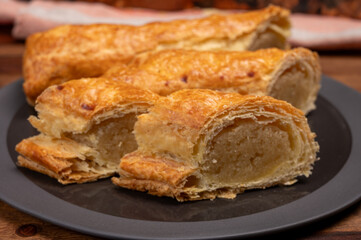 Fresh baked Dutch filled spicy cookies from puff pastry with almonds on black board close up