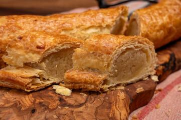 Fresh baked Dutch filled spicy cookies from puff pastry with almonds on wooden board close up