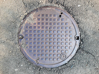 Rusty manhole cover on asphalt street. Service holes. Groundwater drainage. cast iron cover