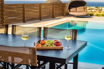 Terrace Tranquility: White Wine, Fresh Fruits, and Poolside Bliss on a Summer Day. Image convey the luxury and relaxation of a leisurely terrace retreat on a sunny summer day.