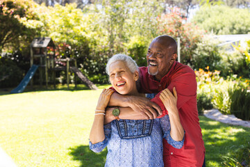 Happy diverse senior couple embracing in sunny garden