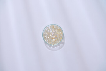 View from above of vitamin E capsules displayed in a petri dish on a white background. Vitamin E helps skin smooth, youthful, and reduces wrinkles.