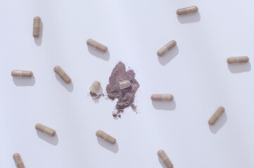 Gray hard capsules are randomly arranged on a white background. Capsules are convenient to use and easy to store and transport because they are dosed and packaged neatly like tablets.