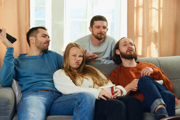 Group portrait of young people, lovely couple with friends, with unhappy faces sitting on sofa...