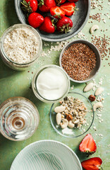 Healthy vegan breakfast ingredients, coconut yogurt, oat-flakes, nuts, linseed and berries , top view