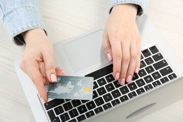 Fototapeta na wymiar Online payment. Woman using credit card and laptop at white wooden table, top view