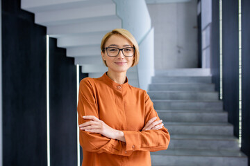 Portrait of young beautiful woman at workplace inside office, blonde business woman with crossed...