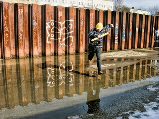 berlin, deutschland - 25.02.2010 - bauarbeiter mit wasserwaage springt über eine pfütze