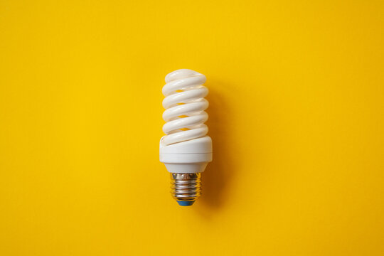 Energy saving light bulb on a orange background. Economical consumption of electricity. The concept of nature conservation