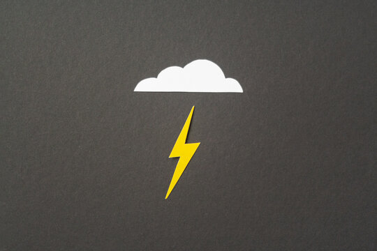 White cut out paper cloud and yellow lightning on black background. weather concept. Energy and electricity. Nature