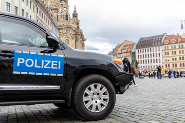 German Police black SUV car at Dresden Altstadt city street on New Market square Neumarkt for safety reasons at demonstration protest activists meeting. Armored policeman vehicle at Germany Saxony - obrazy, fototapety, plakaty