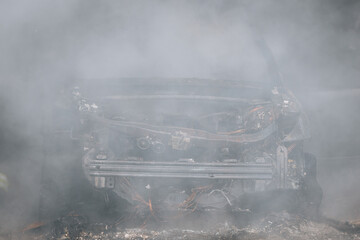 Firefighters extinguish a burning car in a garage. Burnt car. Rescuers. Strong smoke. Emergency....