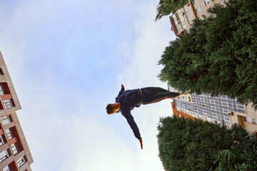 Fish eye effect photo of young man, guy performing insane tricks and breathtaking flips in air in...