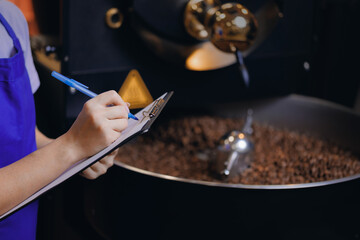 Worker use tablet for checks quality on professional mixing roaster machine, process roasting...