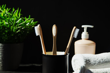Natural bamboo toothbrushes, plant, towels on a black background.