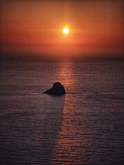 the lonly rock in the sea by the sunset - obrazy, fototapety, plakaty