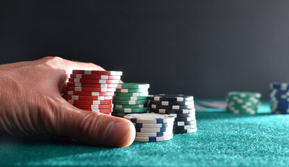 Naklejka premium Hand betting game chips on mat and isolated dark background