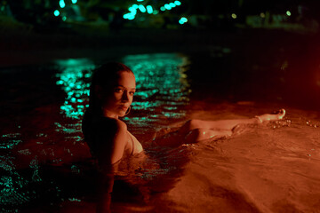 Woman immersed in lagoon waters at night, radiates feminine grace amidst nature. Elegant female...