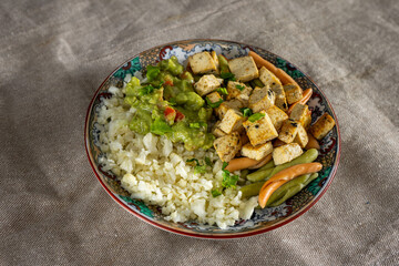 Vibrant cauliflower 'rice' bowl with marinated tofu, colorful pasta, and creamy avocado guacamole. A colorful, healthy feast!